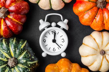 Siyah masada bir çalar saat ve balkabağı..