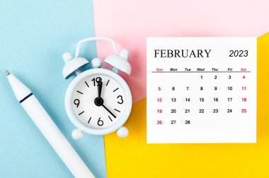 Güzel arka planda alarm saati ve kalemle birlikte Şubat 2023.