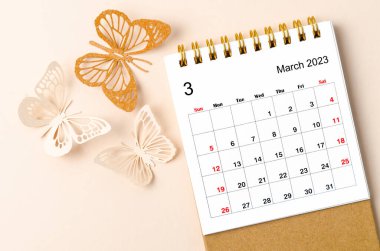 Mart 2023 Sarı zemin üzerinde planlama ve hatırlatma için düzenleyici için masa takvimi ve kelebek paer.