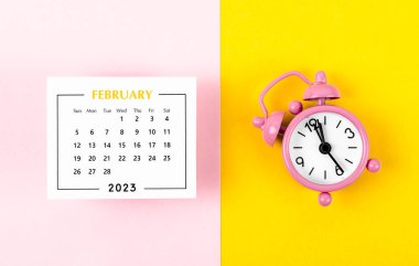 2023 yılının Şubat ayının takvimi. Arka planda pembe alarm saati var..