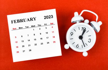 February 2023 Monthly calendar year with alarm clock on red background.