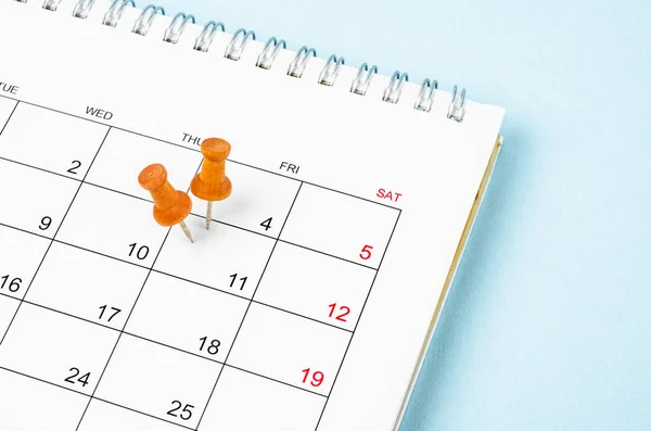 Embroidered wooden pins on a blank calendar on the Friday 11th with selective focus on blue background.