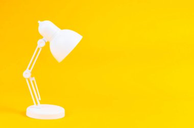 White folding table lamp on yellow background.