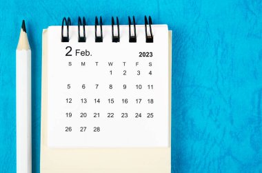 February 2023 Monthly desk calendar for 2023 with pencil on blue background.
