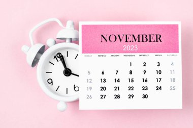 November 2023 Monthly calendar year with alarm clock on pink colour background.