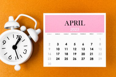 April 2023 Monthly calendar for the organizer to plan 2023 year with alarm clock on yellow background.
