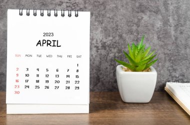 April 2023 Monthly desk calendar for 2023 with diary on wooden table.