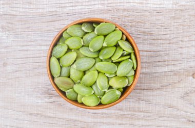 Raw Green Organic Pumpkin Seed Pepitas in a Bowl on wooden background.