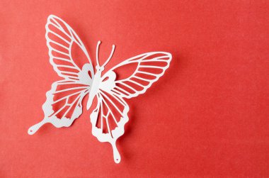 White paper butterfly carve on a red background with empty space.