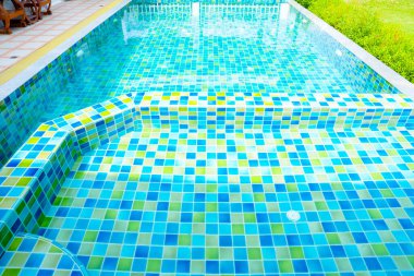 Macro from Swimming pool with clear blue water in a garden area, surrounded by plants