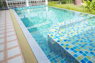 Macro from Swimming pool with clear blue water in a garden area, surrounded by plants