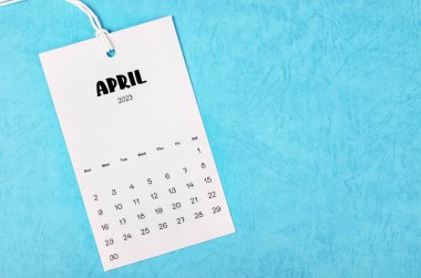 2023 April calendar page hanged on white rope  on blue background.