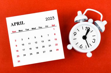 April 2023 Monthly calendar year with alarm clock on red background.