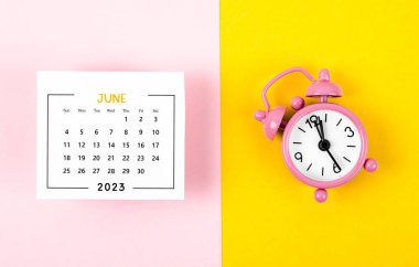 2023 Haziran 'ının takvimi. Güzel bir arka planda pembe alarm saati var..