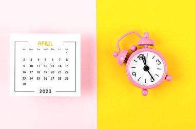 April 2023 Monthly calendar for 2023 year with pink colour alarm clock on beautiful background.