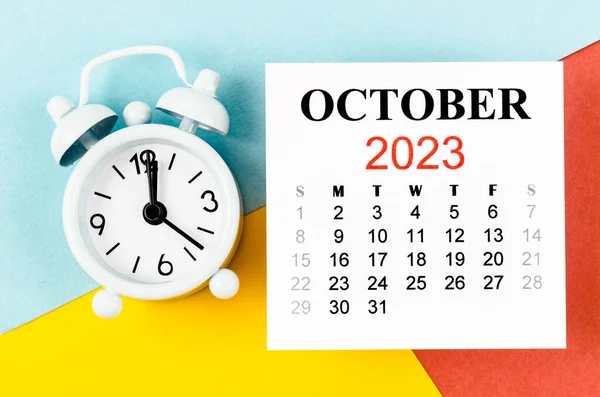 2023年10月カラフルな背景に目覚まし時計と毎月の暦年 — ストック写真