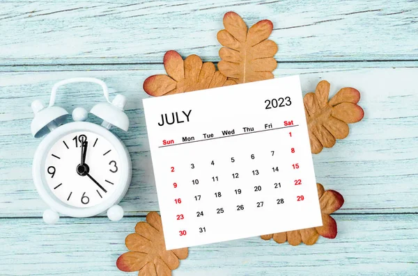 2023年7月每月日历年和蓝木背景干叶闹钟 — 图库照片