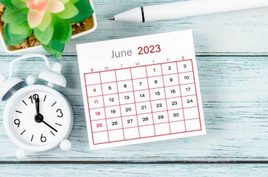 Haziran 2023 Aylık takvim yılı ve alarm saati mavi ahşap arka planda kalemle.