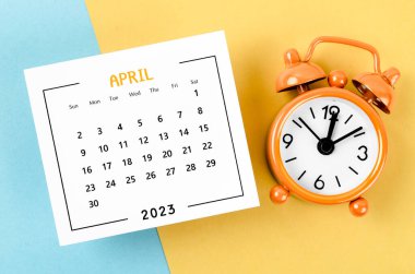 2023 Nisan ayının takvimi. Sarı ve mavi arka planda alarm saati var..