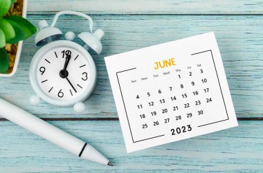 Haziran 2023 Aylık takvim yılı ve alarm saati mavi ahşap arka planda kalemle.
