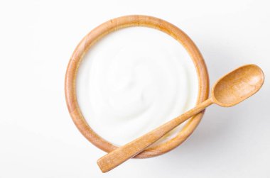 Beyaz arka planda tahta kaşıkla ahşap kasede taze Yunan yoğurdu. Sağlıklı kahvaltı..