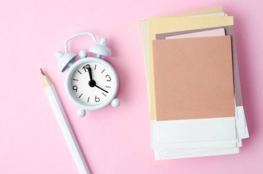 Pembe arkaplan üzerindeki mesaj ve alarm saatiniz için boş kağıt yığını.