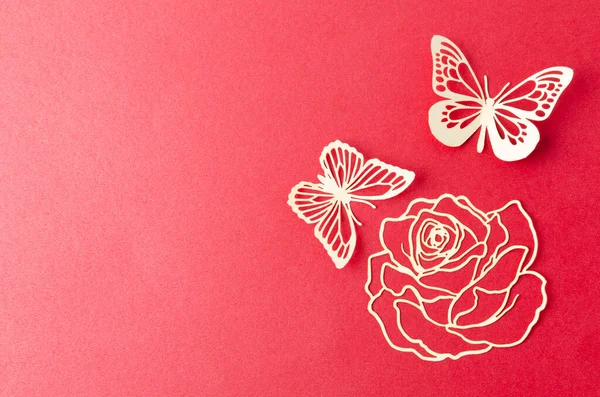 白い紙の蝶と花の彫刻が赤い段ボールの背景に — ストック写真
