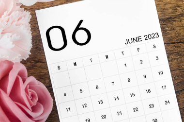 2023 Haziran ayı takvimi. Ahşap arka planda pembe gül..