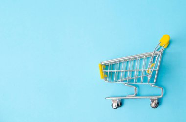 Mavi arka planda boş sarı alışveriş arabası. Minimum düz konsept. 