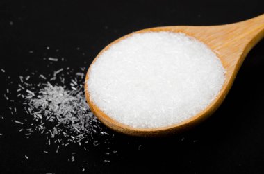 Marco monosodium glutamate (MSG) siyah arka planda tahta kaşıkla