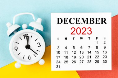 Aralık 2023 Aylık takvim yılı ve renkli arkaplanda alarm saati.
