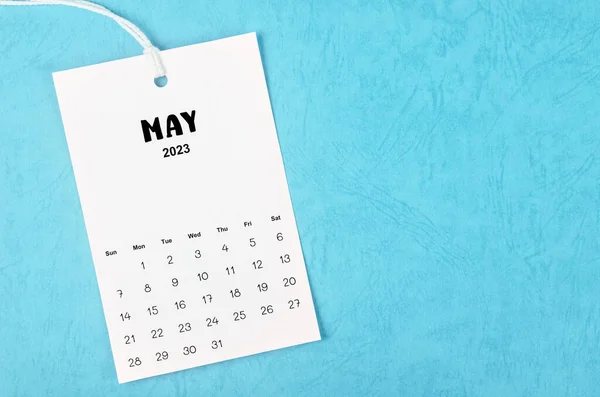 2023 May calendar page hanged on white rope  on blue background.