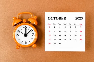 2023 Ekim 'i, organizatörün 2023 yılını sarı arka planda alarm saatiyle planlaması için düzenleyen takvim..