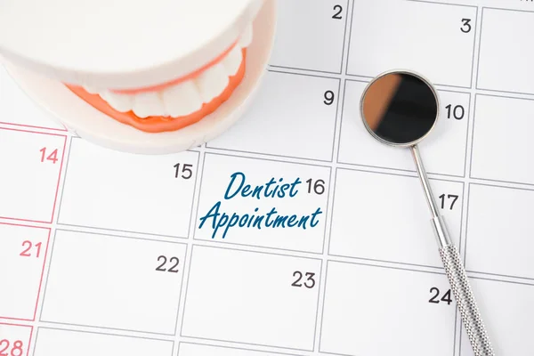 Dentist appointment writing on a calendar page and dentures model with mirror dental.