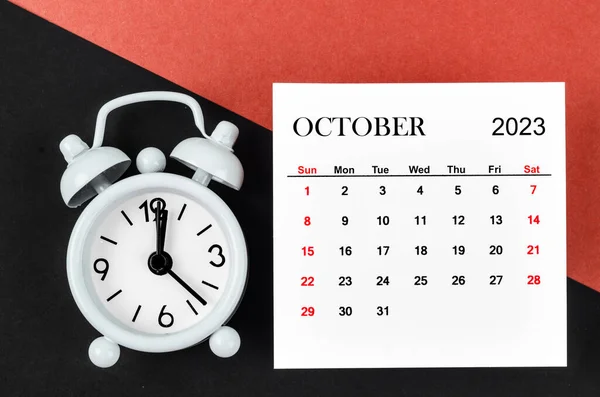 2023年10月赤と黒の背景に目覚まし時計と毎月の暦年 — ストック写真