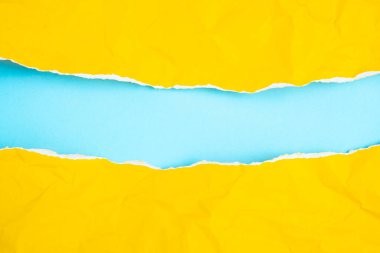 Mavi arkaplan dokusunda yırtık sarı kağıt çerçeve. Boşluğu kopyala.