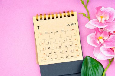 July 2023 calendar desk and pink orchid on pink background. clipart