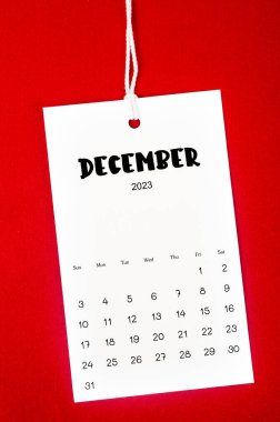 2023 Aralık takvim sayfası Kırmızı zemin üzerinde beyaz ipe asıldı.