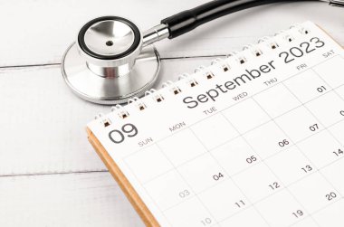 Stetoskop tıbbi ve Eylül 2023 masa takvimi ahşap arka planda, sağlıklı kavramları kontrol etmek için takvim.