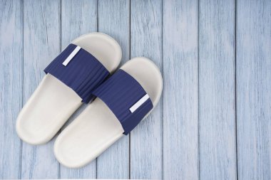 Mavi ahşap arka planda, üzerinde fotokopi alanı olan beyaz ve mavi renkli lastik ayakkabı manzarası. Yaz tatili konsepti.