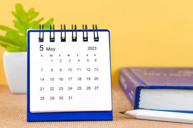 2023 Mayıs ayının masa takvimi. Sarı arkaplan üzerine bir kitap..