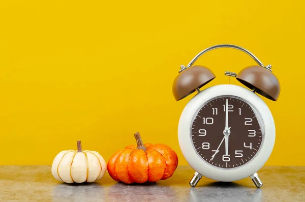 黄色の背景に秋のカボチャとヴィンテージ目覚まし時計 — ストック写真
