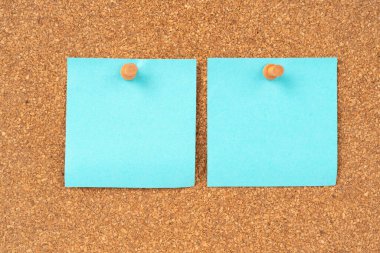 Boş mavi renkli yapışkan not kağıdı ve tahta arka planda tahta raptiye..