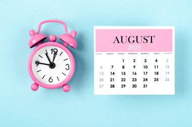 2023 Ağustos 'unun takvimine göre mavi zemin üzerinde pembe renkli alarm saati var..