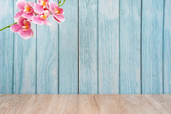 ピンク色の蘭の装飾が施された木製の床と青い壁 背景のための空の部屋 — ストック写真