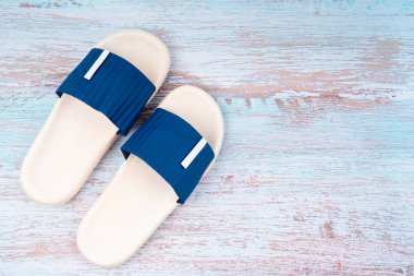 Mavi ahşap arka planda, üzerinde fotokopi alanı olan beyaz ve mavi renkli lastik ayakkabı manzarası. Yaz tatili konsepti.