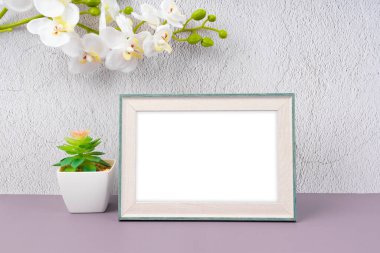 Boş fotoğraf çerçevesi ve beton duvarda beyaz orkide çiçeği, kopyalama alanı ve içerisi için kırpma yolu ile.