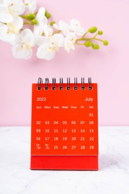 Kırmızı takvim Temmuz 2023. 2023 yılı için masa takvimi ve pembe arka planda pembe orkide..