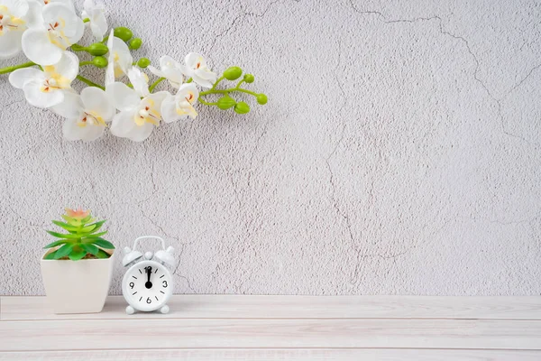 Ahşap Zemin Üzerindeki Alarm Saati Beyaz Orkide Dekorasyonlu Beton Duvar — Stok fotoğraf