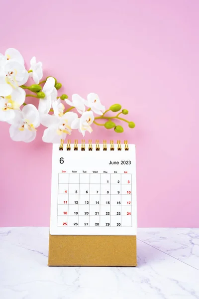 2023年6月デスクカレンダーと大理石の床に白い蘭 — ストック写真